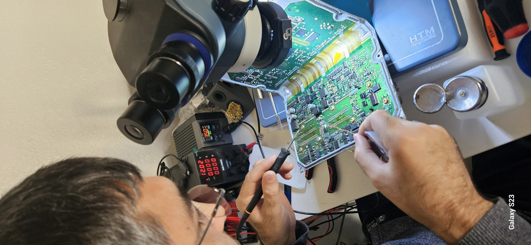 Device Craft technician performing fine-pitch soldering under a microscope